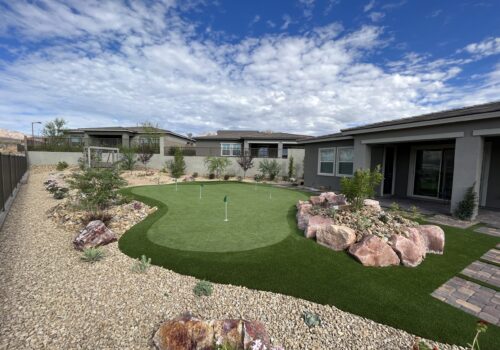 A backyard with a putting green and rocks.