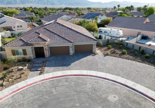 A aerial view of a house with a driveway in the middle.