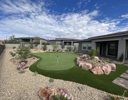A backyard with a putting green and rocks.