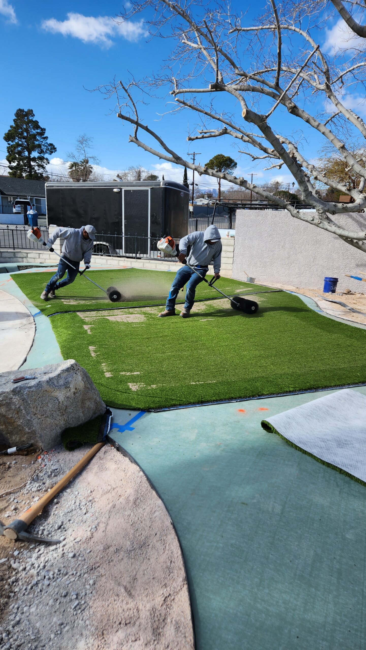 Two men are working on a fake grass field. Two men are working on a fake grass field.