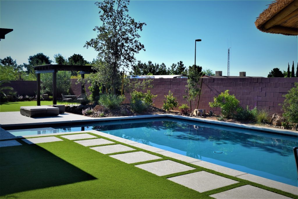 A pool with grass and trees in the background